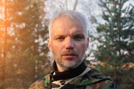 Soldier man standing on the background of the forest. Portrait of a military man tired of the war. Soldier of a mercenary army in Ukraine. War and emotional concept.の写真素材