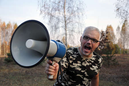 Closeup portrait of a young man screaming into a megaphone. Shout loudlyの写真素材