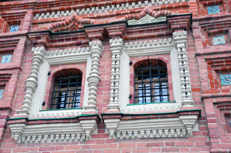 Part of the wall of the facade of a medieval building with barred windows