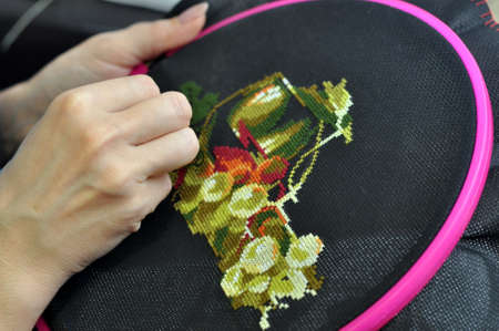 Women's hand embroidery in a hoop, a woman embroiders a pattern on dark material. Close-up. The concept of needlework, hobby, leisure.の写真素材