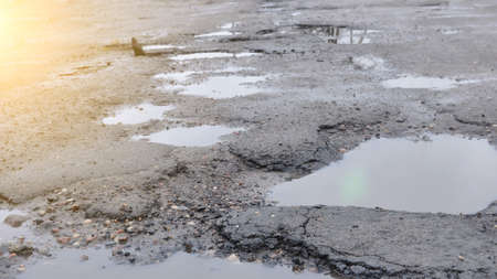 Poor road conditions. Winter season. Holes in the asphalt, the risk of driving a car, poor asphalt, a dangerous road, potholes in the asphalt.の写真素材