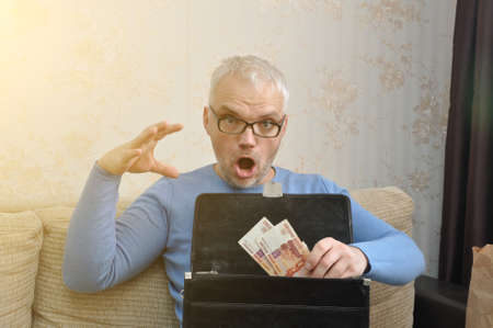 A business man puts money into a black leather briefcase. Business