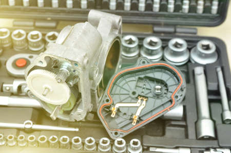 Repair and cleaning the car throttle. Analysis of the throttle on the background of a set of tools...