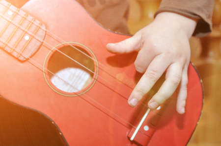 The child plays a children's guitar. Hand on musical instrument. A toy