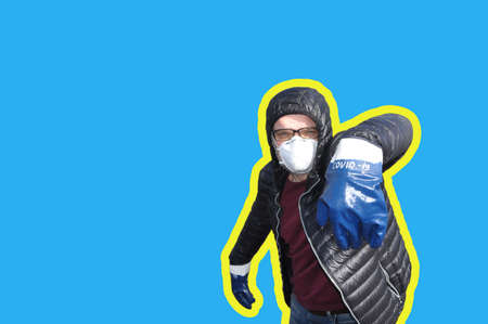 Man in a protective mask and gloves with the inscription COVID-19 Isolated on a blue background. Coronavirus infection protection concept. COVID-19. Pandemicの写真素材
