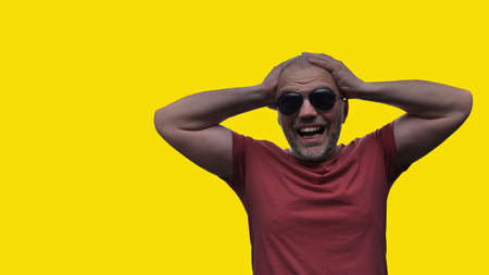 The man holds his hands behind his head and screams from despair and disappointment, his eyes are full of horror, his mouth opened. Horror fearの写真素材