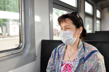 A woman in a medical protective mask rides in public transport. The concept of protection against...