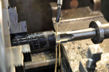Metalworking machine at work. Thread cutting in the workpiece. Lubricating and cooling fluid