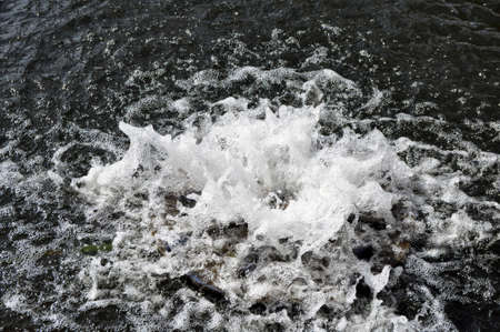 Spring, a stream of water hits through the water surface. Close-upの写真素材