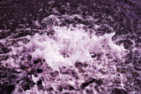Spring, a stream of water hits through the water surface. Close-upの写真素材