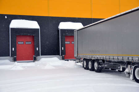 Delivery of goods by truck to a modern warehouse complex in winter.