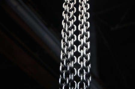 Metal chains dangling and illuminated with bright light. Industry.の写真素材