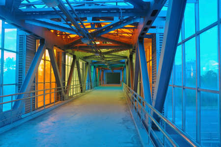 A futuristic pedestrian overpass over a motorway made from a glass steel overpass. Colors of rainbow.の写真素材