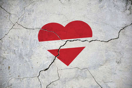 The symbol of the national flag of Latvia in the form of a heart on a cracked concrete wall. concept.の写真素材
