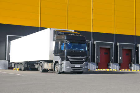 Unloading trucks in a modern warehouse complex. Transportation, storage, logistics.