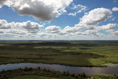 Floodplain of the Pina river with a meadow in a wild landscape and a blue sky with clouds. View from...