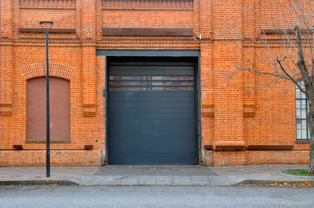 Red brick wall with automatic metal roller doors used in factory, warehouse, garage and industrial warehouse.の写真素材