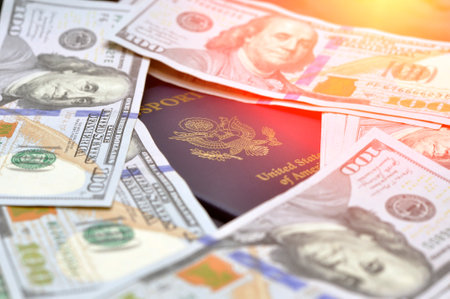 US passports in a pile of US dollar banknotes. US document. Illumination.