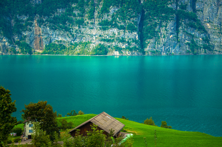 Village house in front of the Lake Walensee and the mountain chain of the Churfirsten Leistchamm, landscape in the Canton St. Gallen, Switzerlandの写真素材