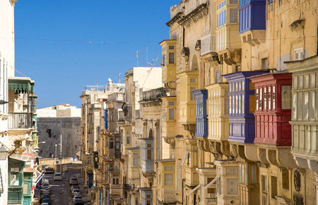 Top view of narrow streets and yellow buildings with colorful balconies and windows in Valletta,...