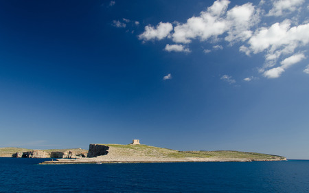 Blue sky and white clouds above Saint Mary's Tower bastioned watchtower on the island of Comino or Kemmuna of the Maltese Archipelago in the Mediterranean Sea, Maltaの写真素材