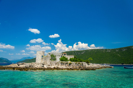 Monastery and church Vavedenja Presvete Bogorodice on island Mala Gospa near Zanjic on Lustica peninsula, Boka Kotor bay with blue turquoise paradise water, blue sky, white clouds, Montenegroのeditorial素材