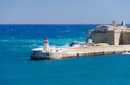 View of the harbor entrance and old medieval Ricasoli East Breakwater with lighthouse and Fort Ricasoli seen from Valletta, Maltaの写真素材