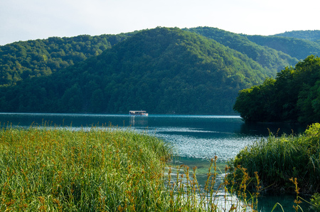 Beautiful lake with boat on blue water between green hills, National park Plitvice Lakes, Croatia, Europeの写真素材