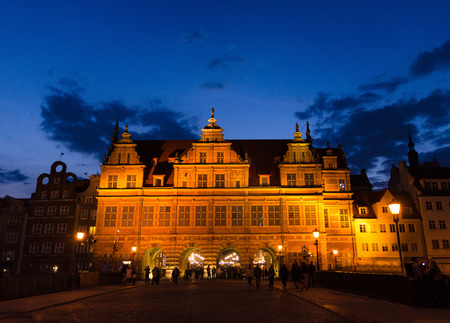 Green gate Zielona Brama building and street lamps lights on bridge over Motlawa river and dark blue sky background in the evening at night, sunset, dusk, twilight, Gdansk, Pomerania, Polandのeditorial素材