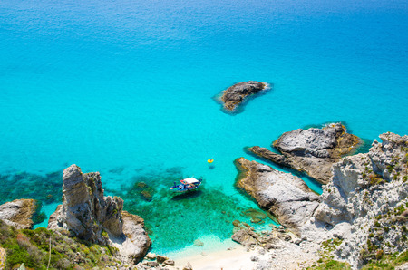Fishing yacht with shadows on bottom sail drift and rubber boat park in lagoon blue azure turquoise water surface of sea among rocks not far from cape Capo Vaticano Ricadi, Calabria, Southern Italyの写真素材