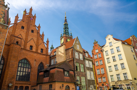 Artus Court brick building, facade of beautiful typical colorful houses with City Hall spire and clock tower blue sky background in old historical town centre, Gdansk, Polandのeditorial素材