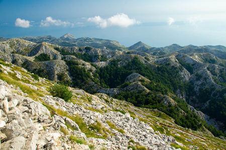 Very curvy road to the steep mountain peak of Sveti Jure in front of hills and rocks of Biokovo mountain range with cloudy sky, Dalmatia, Croatiaの写真素材