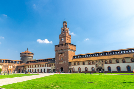 Tower Torrione del Carmine, La torre del Filarete and brick walls of old medieval Sforza Castle Castello Sforzesco, green lawn of courtyard, blue sky white clouds background, Milan, Lombardy, Italyのeditorial素材