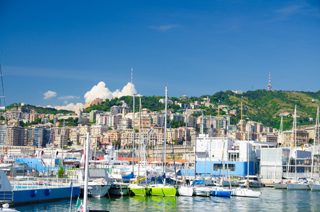 Port Porto Antico harbor with luxury white yachts in historical centre of old european city Genoa Genova with blue sky in clear summer day and green hill with buildings background, Liguria, Italyの写真素材