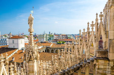 White marble statues on roof of famous Duomo di Milano Cathedral and top aerial view of Milan city with blue sky, Lombardy, Italyの写真素材