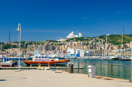 Port Porto Antico harbor with luxury white yachts in historical centre of old european city Genoa Genova with blue sky in clear summer day and green hill with buildings background, Liguria, Italyの写真素材