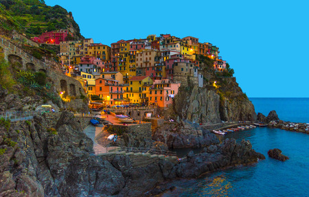 Manarola traditional typical Italian village in National park Cinque Terre with colorful multicolored buildings houses on rock cliff and marine harbor, night evening view, La Spezia, Liguria, Italyの写真素材