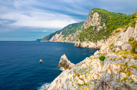 Grotta di Lord Byron with blue water, coast with rock cliff, yellow boat and blue sky near Portovenere town, Ligurian sea, Riviera di Levante, National park Cinque Terre, La Spezia, Liguria, Italyの写真素材
