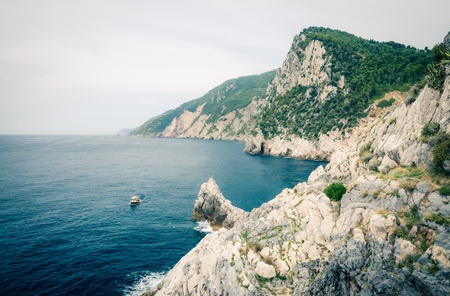 Grotta di Lord Byron with blue water, coast with rock cliff, yellow boat and blue sky near Portovenere town, Ligurian sea, Riviera di Levante, National park Cinque Terre, La Spezia, Liguria, Italyの写真素材