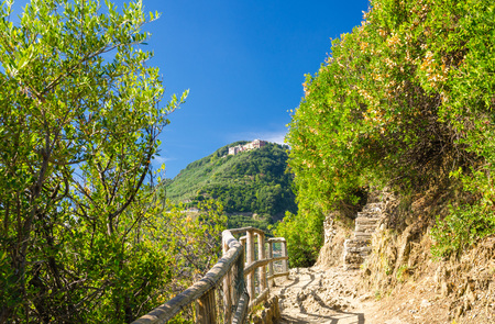 Pedestrian hiking stone path trail with railing between Corniglia and Vernazza villages with green trees, blue sky background, National park Cinque Terre, La Spezia province, Liguria, Italyの写真素材