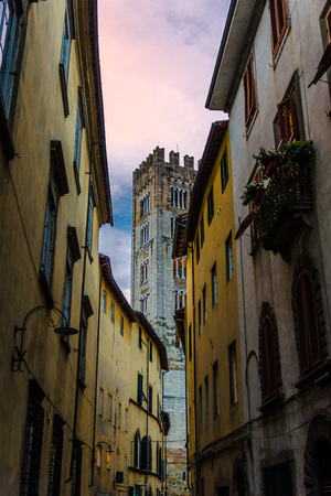 Bell tower of Chiesa di San Frediano catholic church view through narrow street in historical centre of old medieval town Lucca, evening view, Tuscany, Italyの写真素材