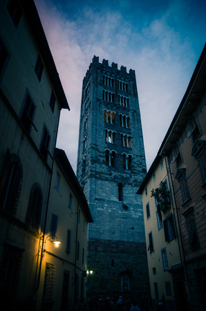 Bell tower of Chiesa di San Frediano catholic church view through narrow street with lamp light in historical centre of old medieval town Lucca, evening view, Tuscany, Italyの写真素材