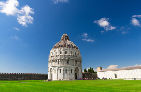Pisa Baptistery Battistero di Pisa on Piazza del Miracoli Duomo square green grass lawn, city wall, Camposanto cemetery, blue sky with white clouds copy space background in sunny day, Tuscany, Italyの写真素材