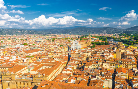 Top aerial panoramic view of Florence city historical centre, Basilica di Santa Croce di Firenze, buildings houses with orange red tiled roofs, hills range, blue sky white clouds, Tuscany, Italyの写真素材