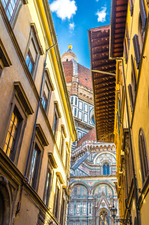 Dome of Florence Duomo, Cattedrale di Santa Maria del Fiore, Basilica of Saint Mary of the Flower Cathedral, buildings on narrow street in historical city centre, view from below, Tuscany, Italyの写真素材