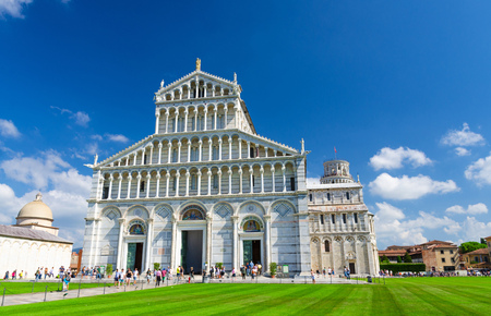 Pisa Cathedral Duomo Cattedrale and Leaning Tower Torre on Piazza del Miracoli square green grass lawn, blue sky with white clouds background in sunny day, Tuscany, Italyの写真素材