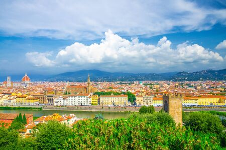 Top aerial panoramic view of Florence city with Duomo Santa Maria del Fiore cathedral, Basilica di Santa Croce, buildings with orange red tiled roofs, Arno river, blue sky white clouds, Tuscany, Italyの写真素材
