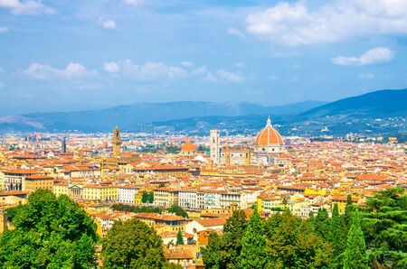 Top aerial panoramic view of Florence city with Duomo Cattedrale di Santa Maria del Fiore cathedral, buildings houses with orange red tiled roofs and hills range, blue sky white clouds, Tuscany, Italyの写真素材