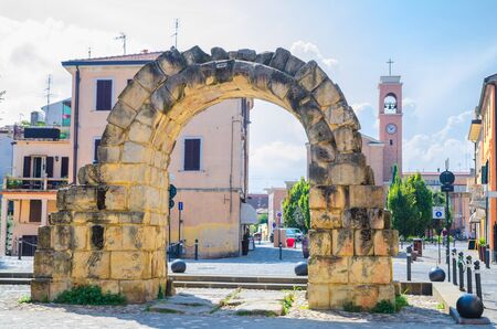 Ruins of ancient stone arch Porta Montanara Gate and Parrocchia di San Gaudenzo church in old historical touristic city centre Rimini with blue sky background, Emilia-Romagna, Italyの写真素材
