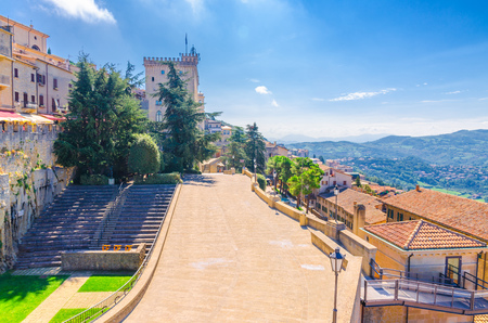 View of streets, square and Palazzo Pubblico palace building in Republic San Marino and landscape with valley, green hills, fields and villages, blue sky and white clouds backgroundのeditorial素材